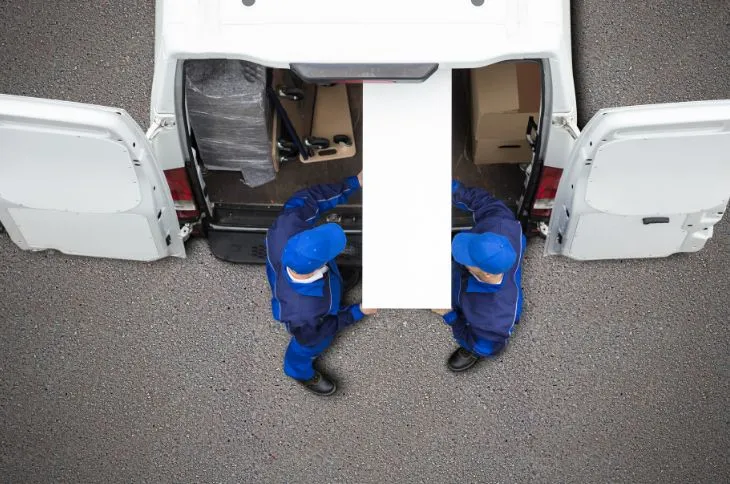 Movers wrapping furniture with protective padding.